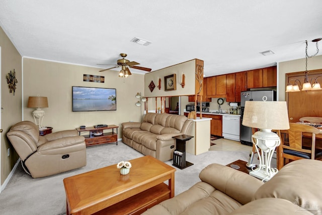 living area with ceiling fan with notable chandelier, visible vents, and light colored carpet