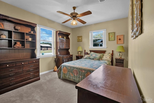 carpeted bedroom with visible vents, baseboards, and a ceiling fan