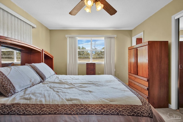 bedroom with a textured ceiling, multiple windows, and a ceiling fan