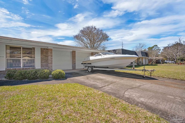 exterior space with brick siding, driveway, an attached garage, and a lawn