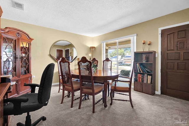 dining area with light carpet, a textured ceiling, visible vents, and baseboards