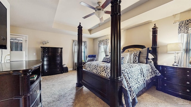 carpeted bedroom featuring a raised ceiling and ceiling fan