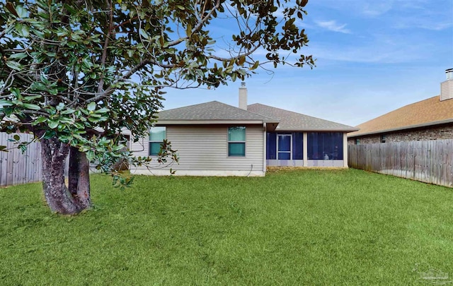 back of property with a yard and a sunroom