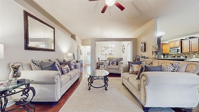 living room with lofted ceiling, ceiling fan with notable chandelier, and dark hardwood / wood-style floors