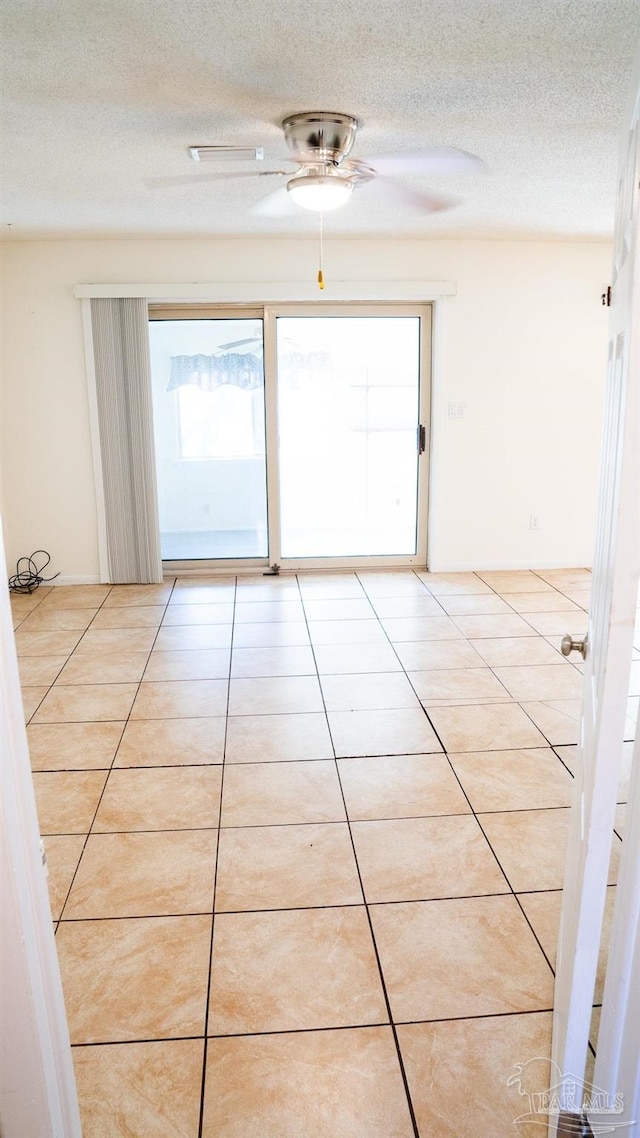 tiled spare room with a textured ceiling and ceiling fan