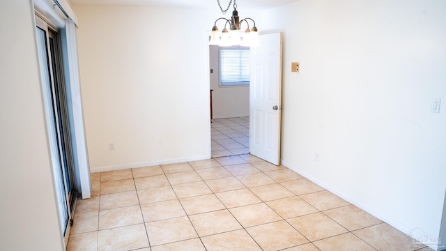 tiled empty room featuring an inviting chandelier