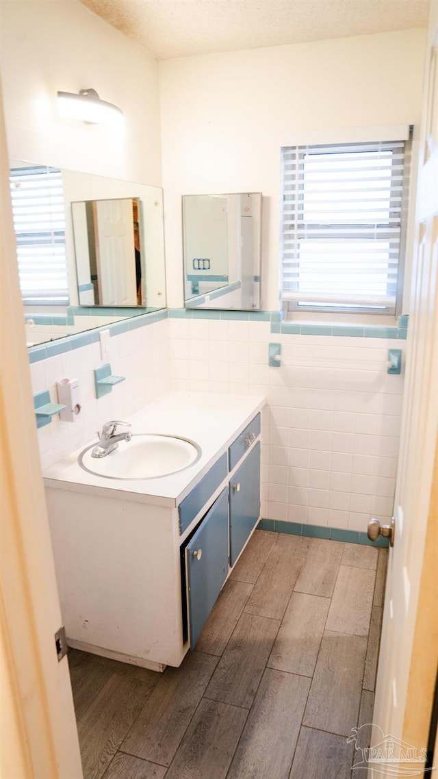 bathroom with vanity, hardwood / wood-style flooring, tile walls, and a textured ceiling