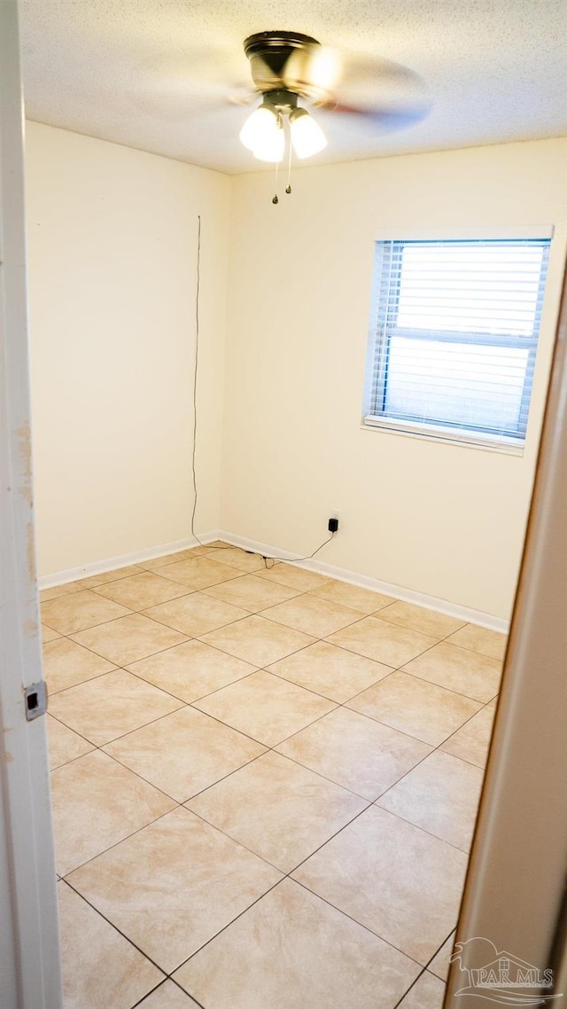 tiled spare room with a textured ceiling and ceiling fan