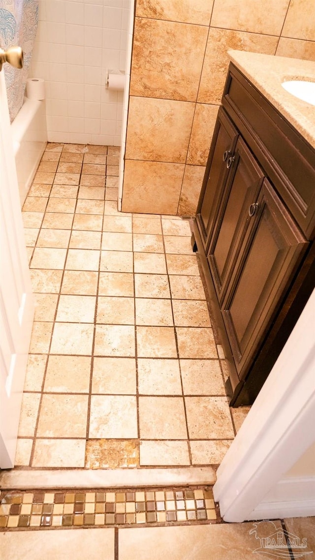 bathroom featuring vanity, tile walls, and a bath