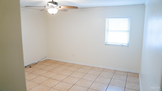 tiled empty room featuring ceiling fan, ornamental molding, and a textured ceiling