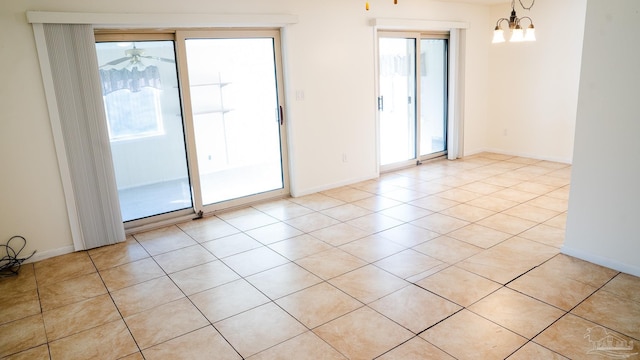 unfurnished room featuring a healthy amount of sunlight, an inviting chandelier, and light tile patterned flooring