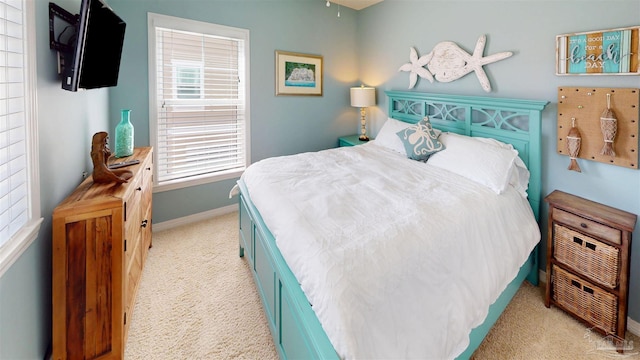 bedroom featuring light colored carpet, baseboards, and multiple windows