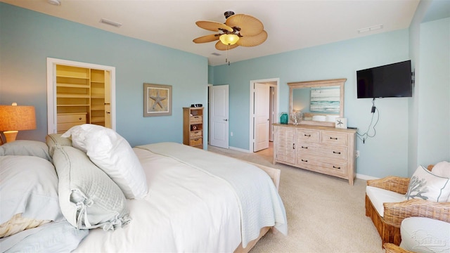 bedroom with baseboards, visible vents, light carpet, and a spacious closet