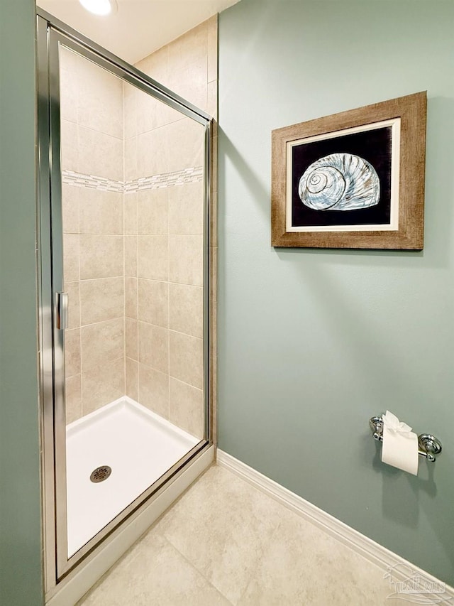 bathroom with baseboards, tile patterned flooring, and a shower stall