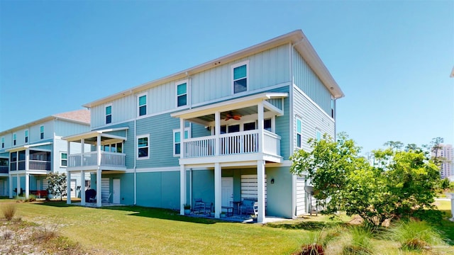 back of house with a ceiling fan, board and batten siding, a yard, and a balcony