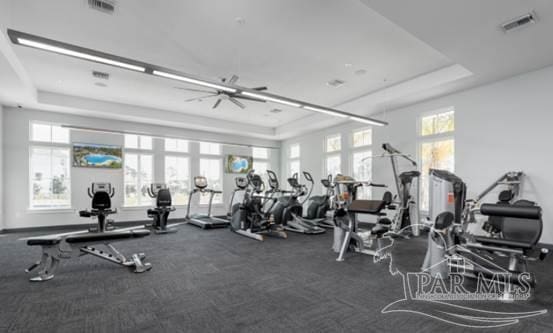 gym featuring a tray ceiling and visible vents