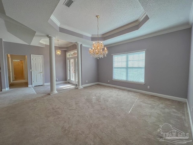 carpeted empty room with a raised ceiling, ornate columns, an inviting chandelier, ornamental molding, and a textured ceiling