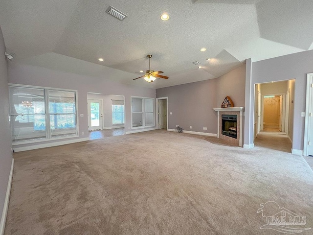 unfurnished living room with a tile fireplace, ceiling fan, light colored carpet, vaulted ceiling, and a textured ceiling