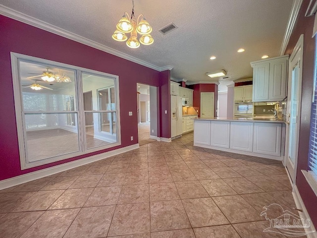 kitchen featuring white cabinets, light tile patterned flooring, crown molding, decorative light fixtures, and a textured ceiling