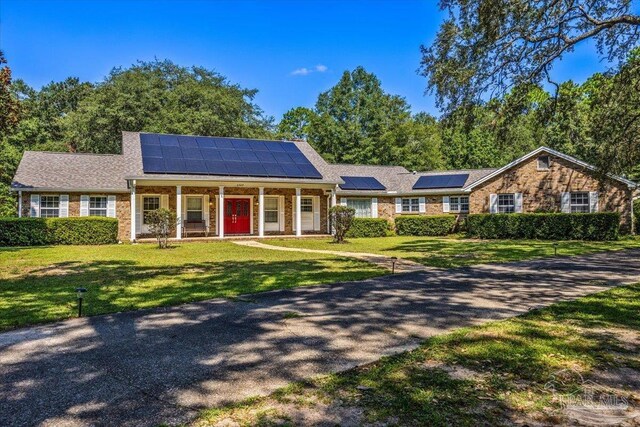 ranch-style home with solar panels and a front lawn