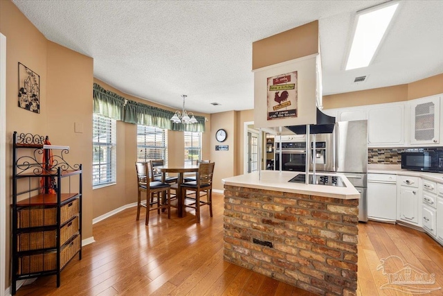 kitchen featuring tasteful backsplash, decorative light fixtures, light hardwood / wood-style flooring, and white cabinets