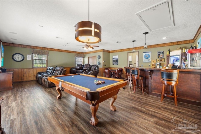 game room featuring wood walls, indoor bar, dark hardwood / wood-style flooring, pool table, and a textured ceiling