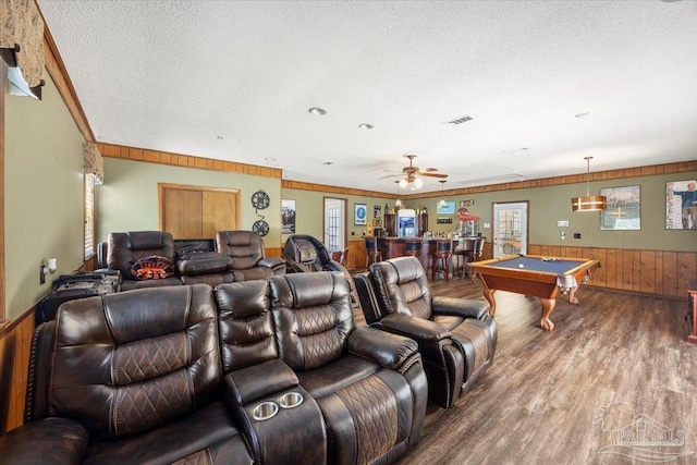 recreation room featuring wood-type flooring, crown molding, a textured ceiling, and wood walls