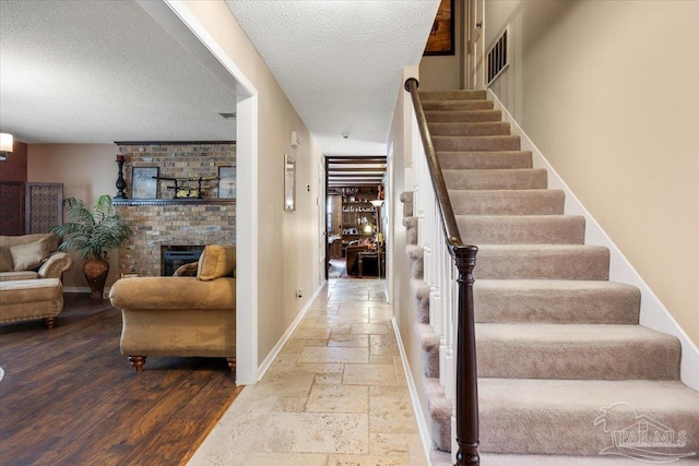 stairway featuring a brick fireplace and a textured ceiling