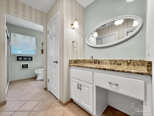 bathroom featuring vanity, a textured ceiling, tile patterned floors, and toilet