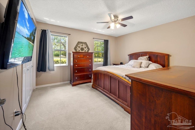 carpeted bedroom featuring ceiling fan and a textured ceiling