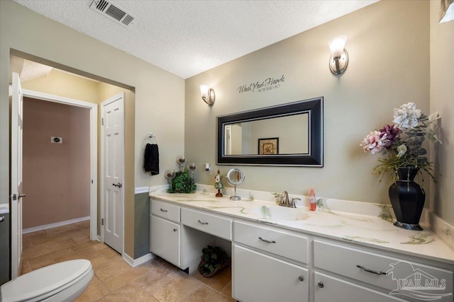 bathroom with vanity, toilet, and a textured ceiling