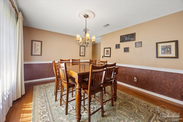 dining area featuring hardwood / wood-style floors, a textured ceiling, and a chandelier