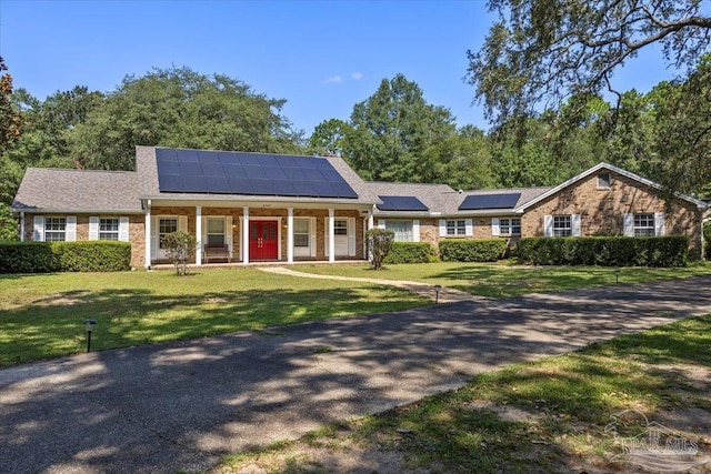 view of front of house featuring a front yard, solar panels, and covered porch