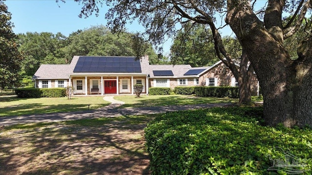 view of front of house with a front yard, solar panels, and covered porch