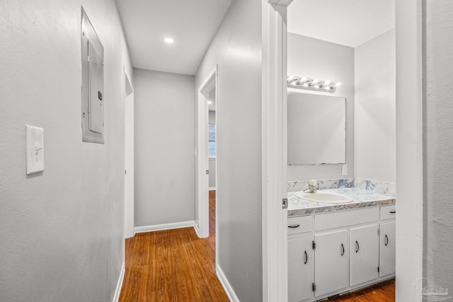 hallway featuring light hardwood / wood-style floors, sink, and electric panel