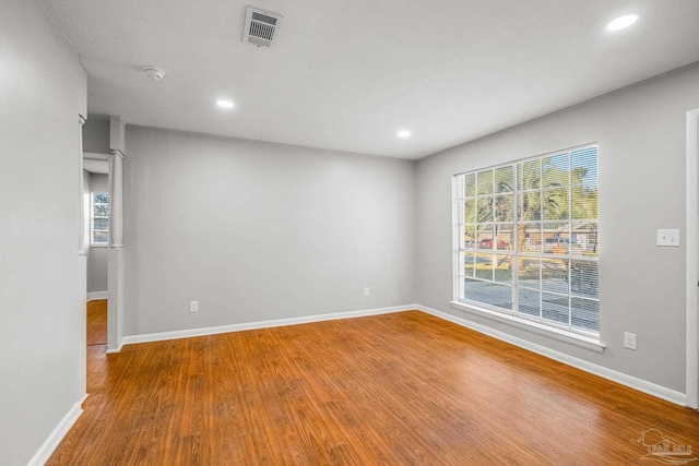 empty room with hardwood / wood-style floors and a healthy amount of sunlight