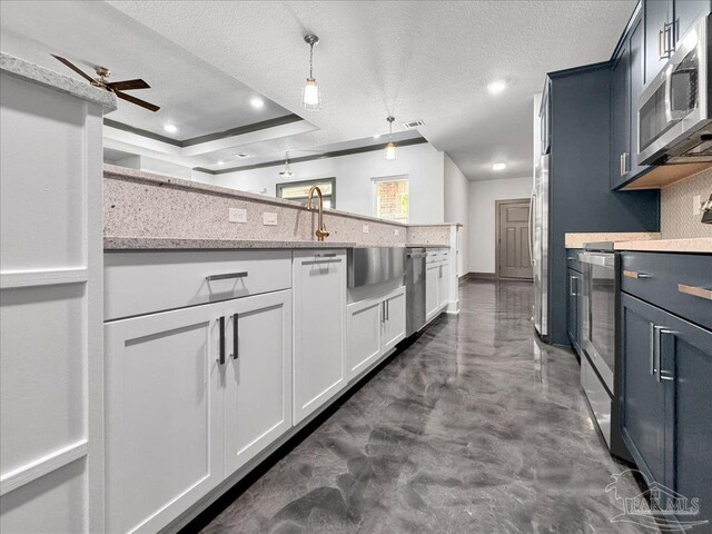 kitchen with appliances with stainless steel finishes, pendant lighting, white cabinets, backsplash, and a textured ceiling