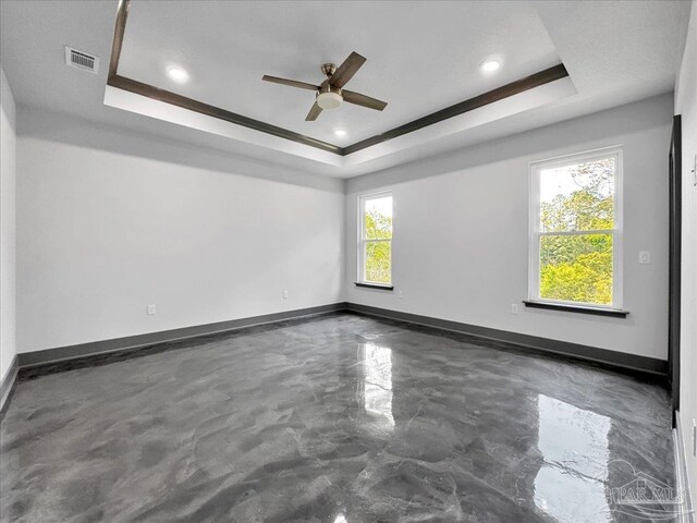 empty room featuring ceiling fan and a tray ceiling