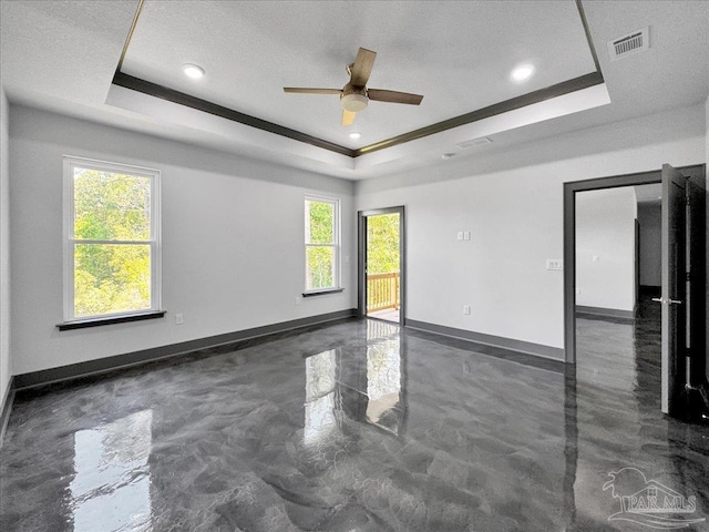 unfurnished room featuring ceiling fan, a textured ceiling, and a tray ceiling