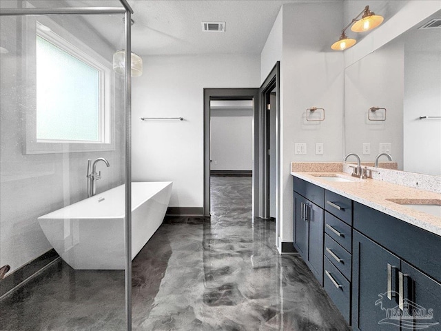 bathroom with concrete flooring, vanity, a textured ceiling, and a tub to relax in