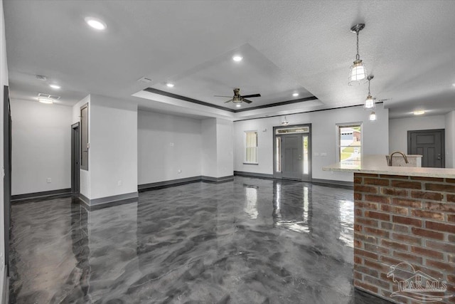 spare room with a raised ceiling, ceiling fan, sink, and a textured ceiling