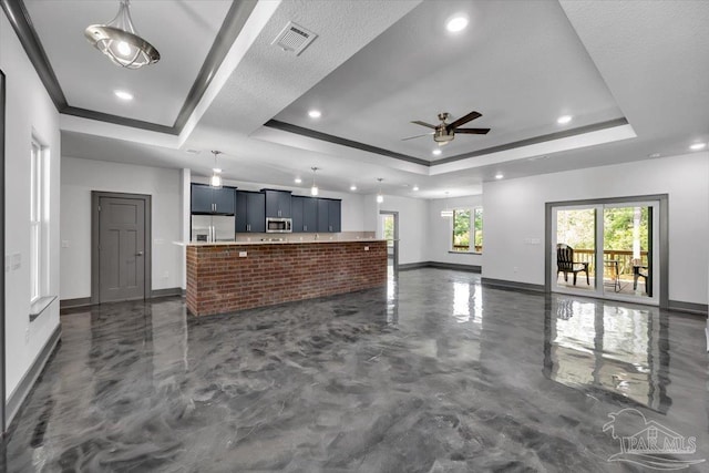 unfurnished living room featuring a tray ceiling, ornamental molding, and ceiling fan