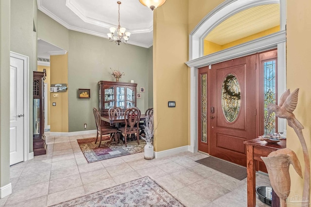 entrance foyer with an inviting chandelier, crown molding, a tray ceiling, and light tile patterned floors