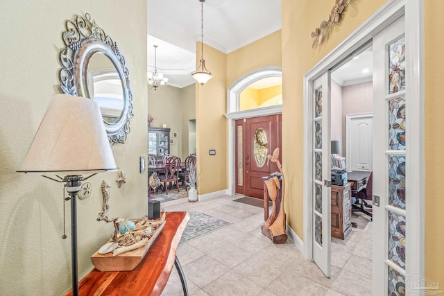 foyer with ornamental molding, an inviting chandelier, and light tile patterned floors