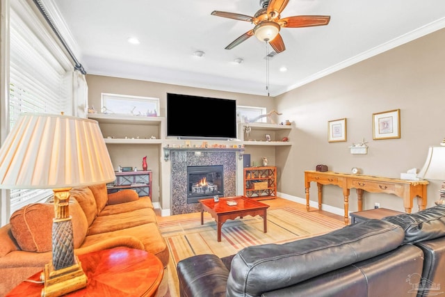 living room featuring ornamental molding, hardwood / wood-style flooring, a tile fireplace, and ceiling fan