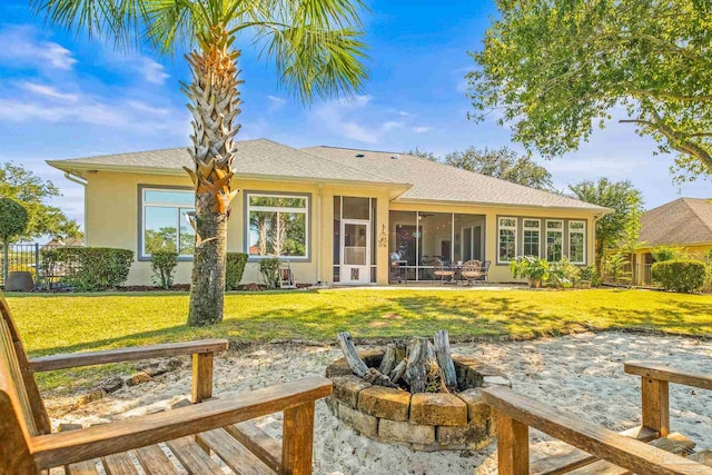 back of property featuring an outdoor fire pit, a patio, a lawn, and a sunroom