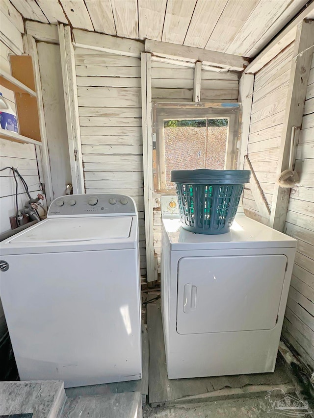 laundry area featuring washer and clothes dryer and wood walls