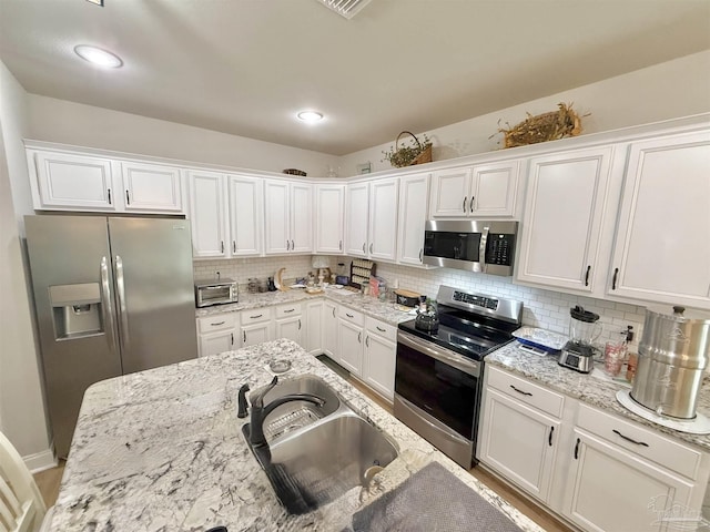 405 Waterbury Ct, Cantonment, FL 32533 - kitchen with appliances with stainless steel finishes, a sink, white cabinets, and decorative backsplash