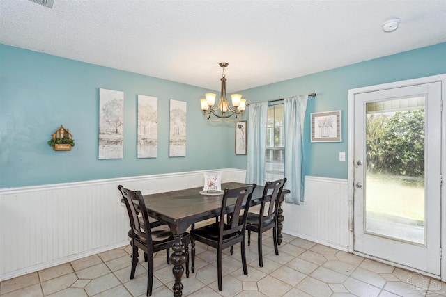 tiled dining space featuring a notable chandelier and a textured ceiling