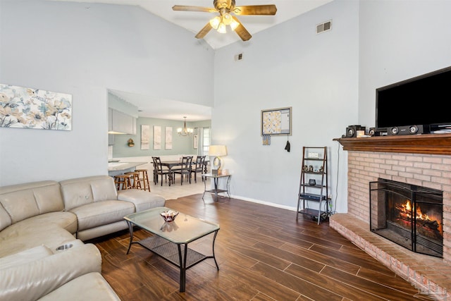 living room with high vaulted ceiling, ceiling fan with notable chandelier, a brick fireplace, and wood-type flooring